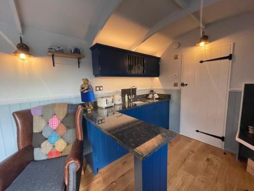 una cucina con armadi blu e piano di lavoro di The Bibury - Westwell Downs Shepherd Huts a Oxford