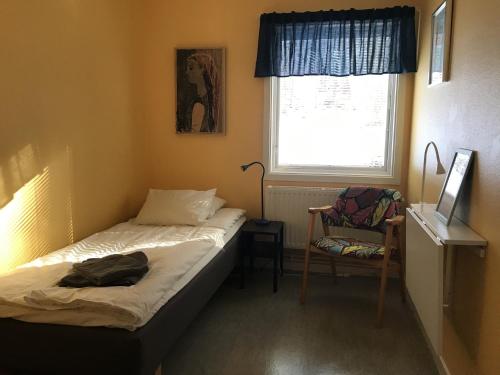 a bedroom with a bed and a chair and a window at Hellidens Slott in Tidaholm