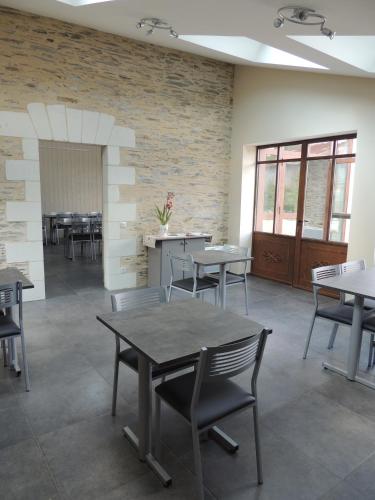 une salle à manger avec des tables et des chaises et un mur en briques dans l'établissement Les Chambres du Meunier, à Juigné-sur-Loire