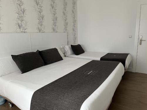 a bedroom with two beds with black pillows at Hotel Avelina in Cangas de Onís
