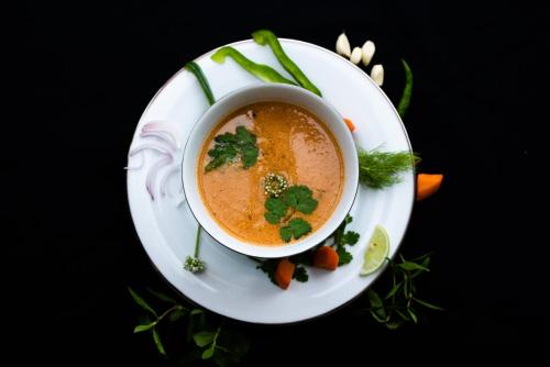 a bowl of soup on a plate with carrots at TROPICAL HOUSE - Jungleside Villa in Hikkaduwa