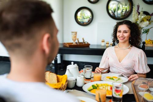 a man and a woman sitting at a table eating food at TROPICAL HOUSE - Jungleside Villa in Hikkaduwa