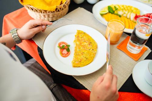 a person sitting at a table with a plate of food at TROPICAL HOUSE - Jungleside Villa in Hikkaduwa