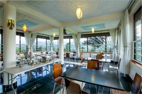 a dining room with tables and chairs and windows at The Crested Crane Bwindi Hotel in Rugando