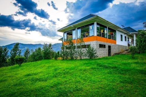 a house on a hill with a green field at The Crested Crane Bwindi Hotel in Rugando