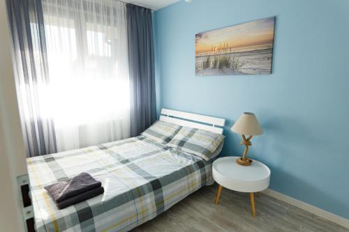 a blue bedroom with a bed and a table and a lamp at Zefir in Darłowo