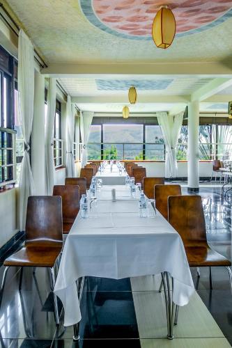 a long dining room with a white table and chairs at The Crested Crane Bwindi Hotel in Rugando