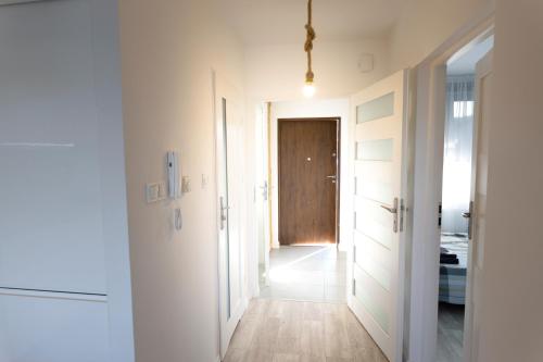 a hallway with white walls and a wooden door at Zefir in Darłowo