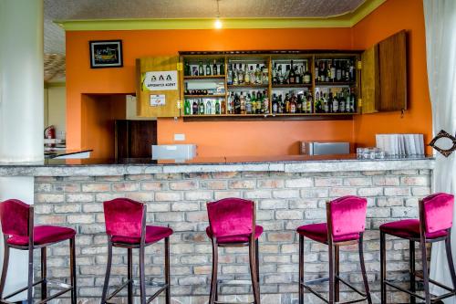 a bar with pink chairs in front of a counter at The Crested Crane Bwindi Hotel in Rugando