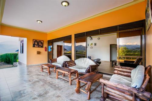 a living room with chairs and beds and windows at The Crested Crane Bwindi Hotel in Rugando