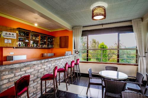 a bar with red chairs and tables and a window at The Crested Crane Bwindi Hotel in Rugando