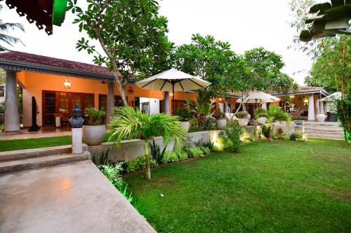 a house with an outdoor yard with an umbrella at TROPICAL HOUSE - Jungleside Villa in Hikkaduwa