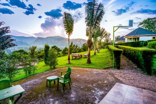 a garden with a table and chairs and palm trees at The Crested Crane Bwindi Hotel in Rugando