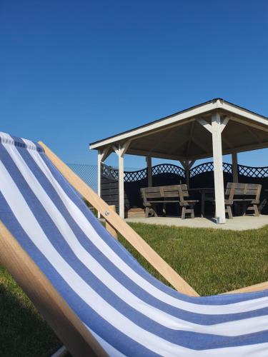 a blue and white hammock in front of a gazebo at Kolory Lata - 365PAM KLIMATYZACJA I PLAC ZABAW W OBIEKCIE in Sarbinowo