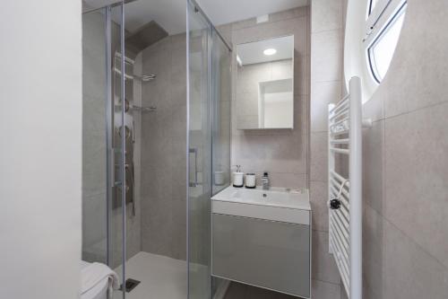 uma casa de banho com uma cabina de duche em vidro e um lavatório. em FLH Olivais Family Flat em Lisboa