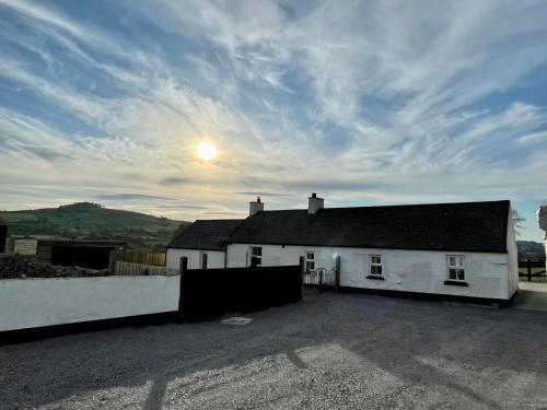 a white house with the sun in the sky at Maggie's Croft Cottages 4 Star Tourism NI in Castlewellan