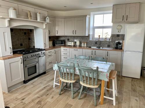 a kitchen with a table with chairs and a sink at Maggie's Croft Cottages 4 Star Tourism NI in Castlewellan