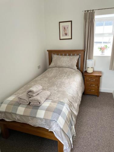 a bedroom with a bed with towels on it at Maggie's Croft Cottages 4 Star Tourism NI in Castlewellan