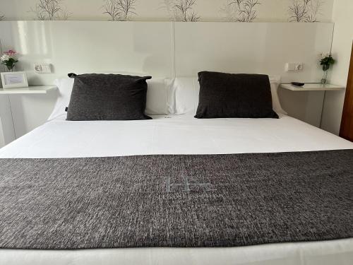 a large white bed with two pillows on it at Hotel Avelina in Cangas de Onís