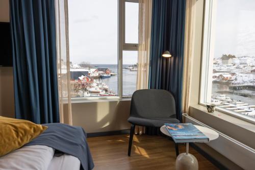 a bedroom with a bed and a chair and a window at The Tide - Hotel in Sørvågen