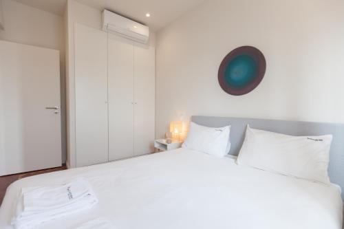 um quarto com uma grande cama branca com almofadas brancas em FLH Estefânia Charming Flat em Lisboa