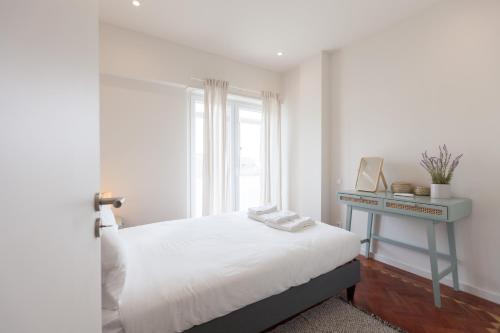 um quarto com uma cama, uma secretária e uma janela em FLH Estefânia Charming Flat em Lisboa