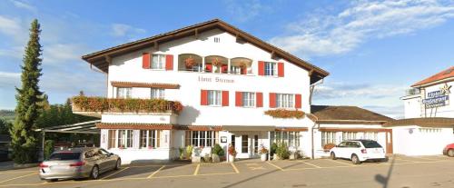 a large white building with cars parked in a parking lot at Hotel Restaurant Sternen in Gelfingen