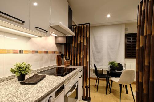 a kitchen with a stove and a table with chairs at El Balconcillo - Apartamento boutique en pleno centro - Grupo Querbes in Gijón