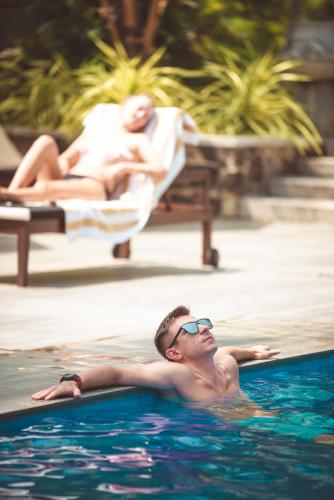 a man in a swimming pool with a woman in the background at TROPICAL HOUSE - Jungleside Villa in Hikkaduwa