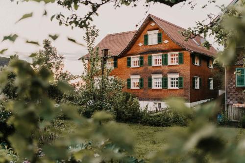une grande maison en briques avec des fenêtres vertes à volets dans l'établissement Mesmerhaus, à Bildstein