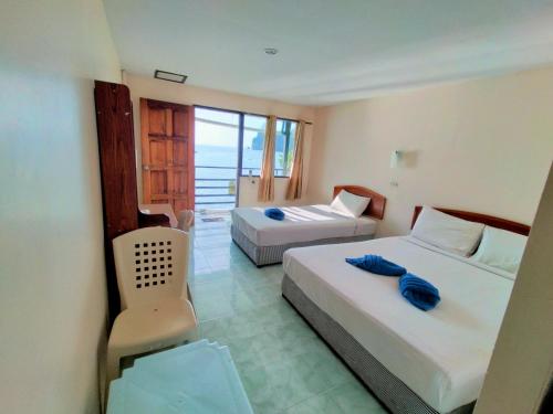 um quarto de hotel com duas camas e uma cadeira em Dalum Beachhouse em Phi Phi Don