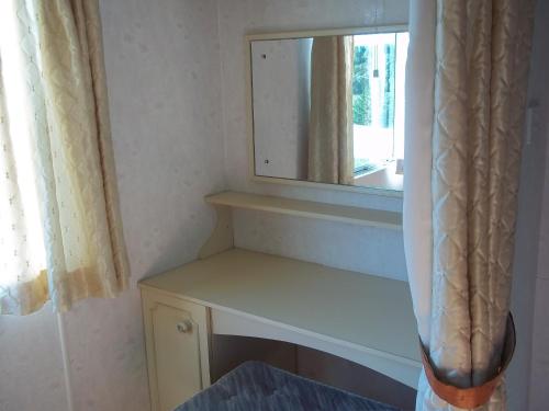 a bathroom with a mirror and a shelf and a window at Višķezers in Višķi