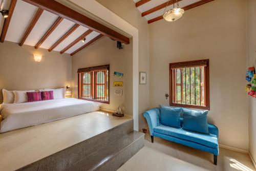 a bedroom with a bed and a blue chair at Saffronstays Casa Del Palms, Alibaug - luxury pool villa with chic interiors, alfresco dining and island bar in Alibaug