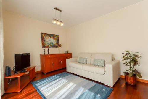 a living room with a white couch and a tv at Sweet Living Viana - City Centre Apartment with Garage in Viana do Castelo