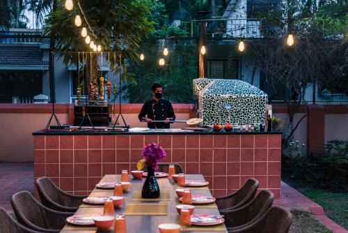 un hombre parado frente a una mesa con comida en Saffronstays Casa Del Palms, Alibaug - luxury pool villa with chic interiors, alfresco dining and island bar, en Alibaug