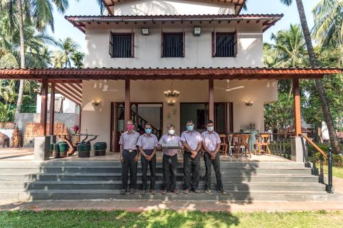 a group of men standing in front of a house at Saffronstays Casa Del Palms, Alibaug - luxury pool villa with chic interiors, alfresco dining and island bar in Alibaug