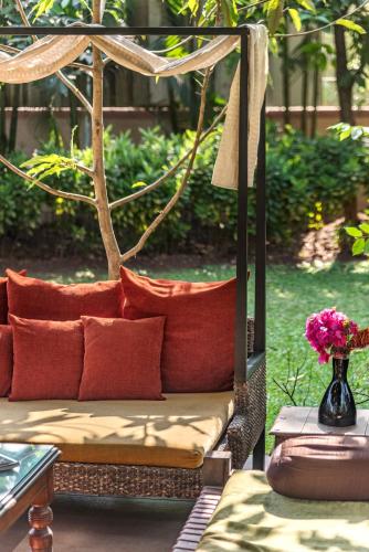 a couch with pillows sitting on a patio at Saffronstays Casa Del Palms, Alibaug - luxury pool villa with chic interiors, alfresco dining and island bar in Alibaug