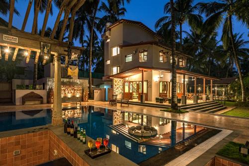 a house with a swimming pool in front of a house at Saffronstays Casa Del Palms, Alibaug - luxury pool villa with chic interiors, alfresco dining and island bar in Alibaug