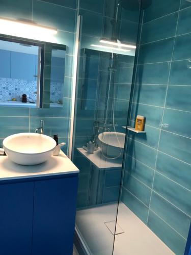bagno blu con lavandino e specchio di Appartement classé, vue mer, clim, wifi, parking a La Grande-Motte