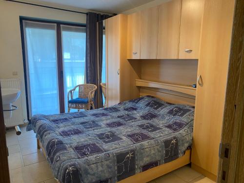 a bedroom with a bed and a chair and a window at Oostduinkerke Apartments in Oostduinkerke