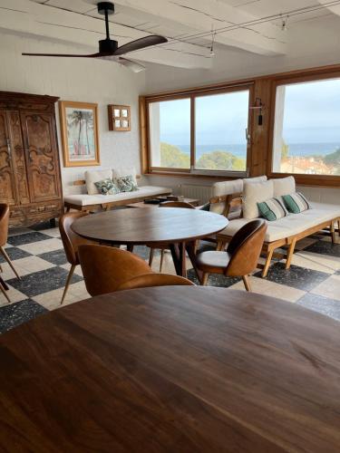 sala de estar con mesas, sillas y ventanas en Villa Paradis, en Les Issambres