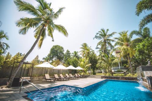 a swimming pool with palm trees and a resort at TROPICAL HOUSE - Jungleside Villa in Hikkaduwa