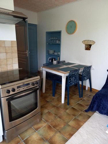 uma cozinha com um fogão e uma mesa com cadeiras em la serenité em Saint-Vivien-de-Monségur