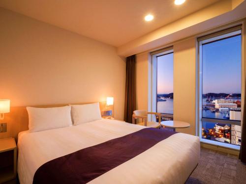 a hotel room with a bed and a large window at Mercure Yokosuka in Yokosuka