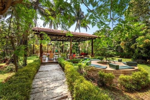 a garden with a wooden pergola and a patio at Saffronstays Casa Del Palms, Alibaug - luxury pool villa with chic interiors, alfresco dining and island bar in Alibaug