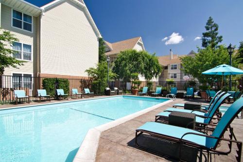 a swimming pool with lounge chairs and an umbrella at Sonesta ES Suites Fresno in Fresno