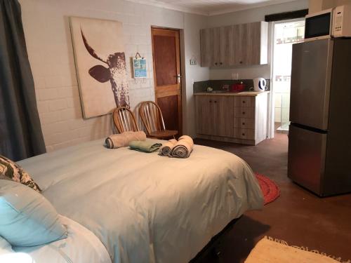 a bedroom with a bed with two chairs and a refrigerator at Old Cape on the Marina - De Pond : Unit 6 in Velddrif