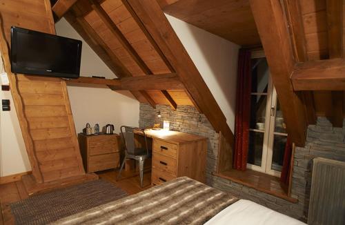 a bedroom with a bed and a desk and a television at Le Moulin de Lily in Palaiseau