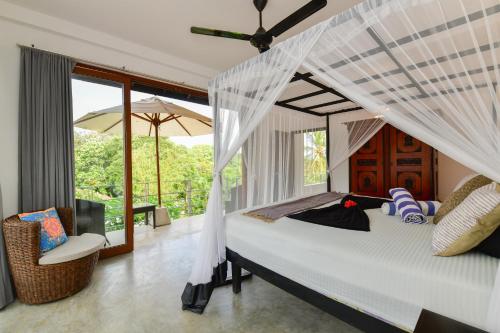 a bedroom with a bed with a mosquito net at TROPICAL HOUSE - Jungleside Villa in Hikkaduwa