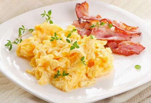 a plate of scrambled eggs and bacon on a table at Hotel Porto Azzurro in Sirmione